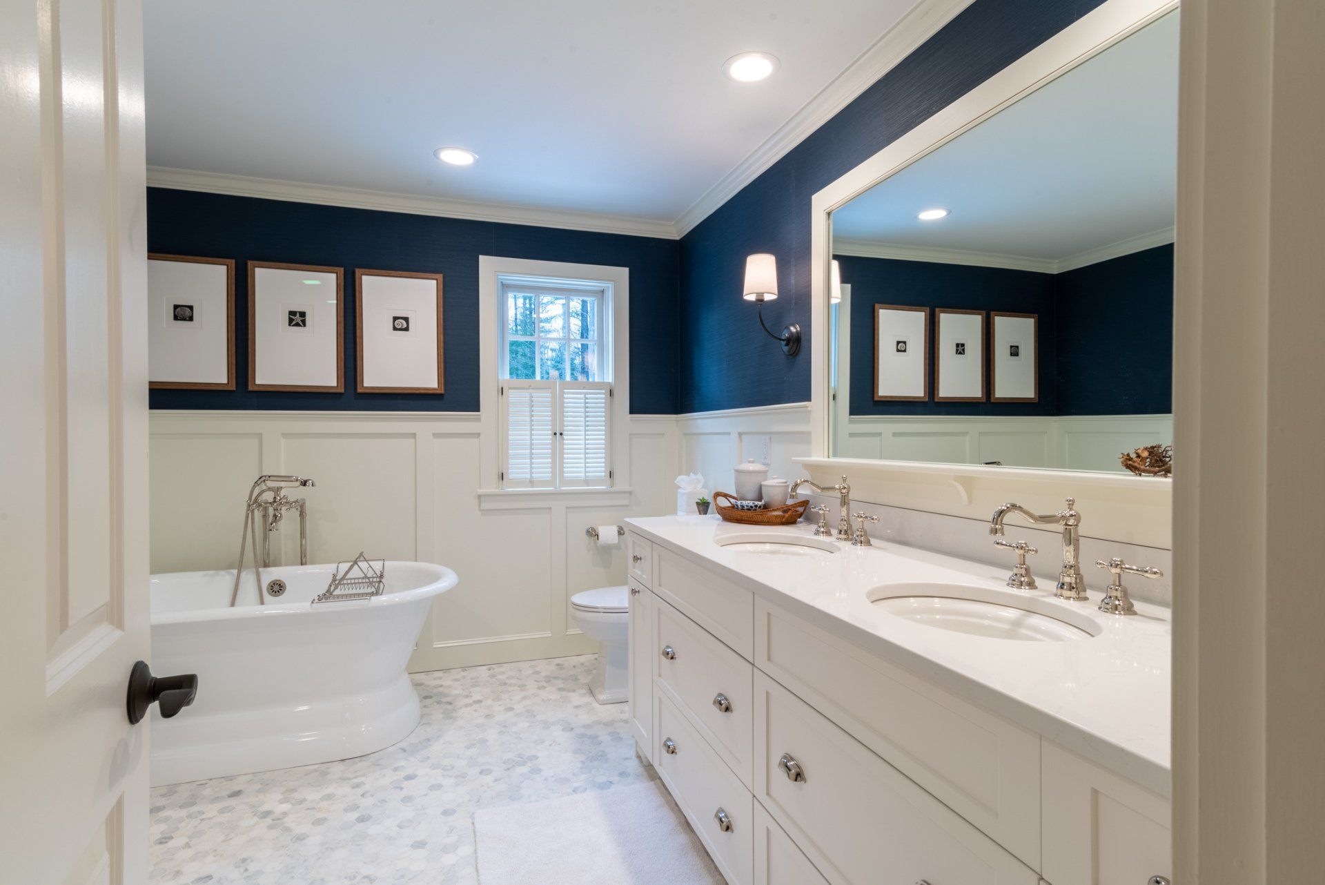 Bright white bathroom with navy walls, freestanding tub, double vanity, and large mirror