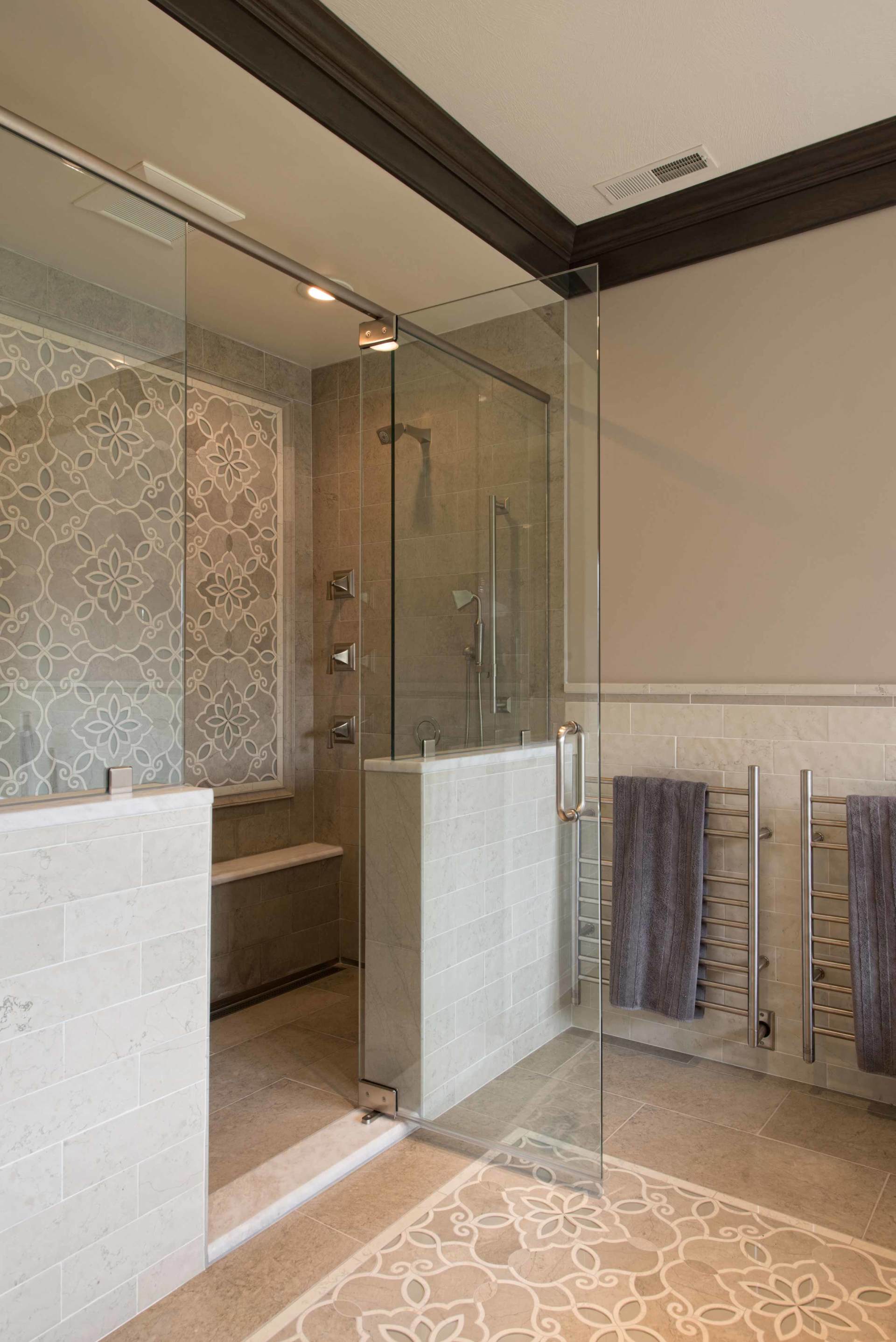 Modern bathroom with glass shower enclosure, white tile, and patterned floor tiles