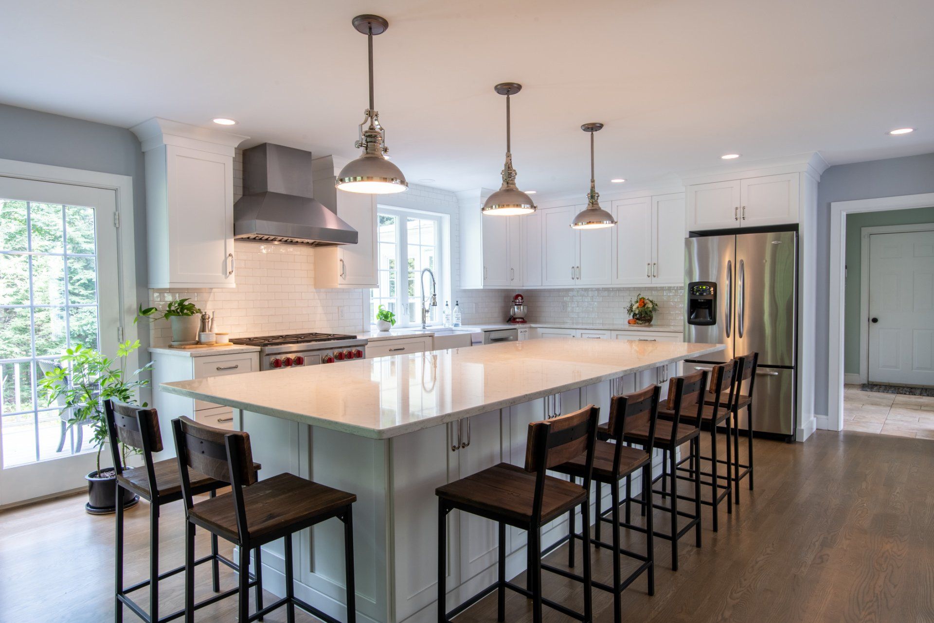 Bright modern kitchen with a large island, pendant lights, bar stools, and stainless steel appliances