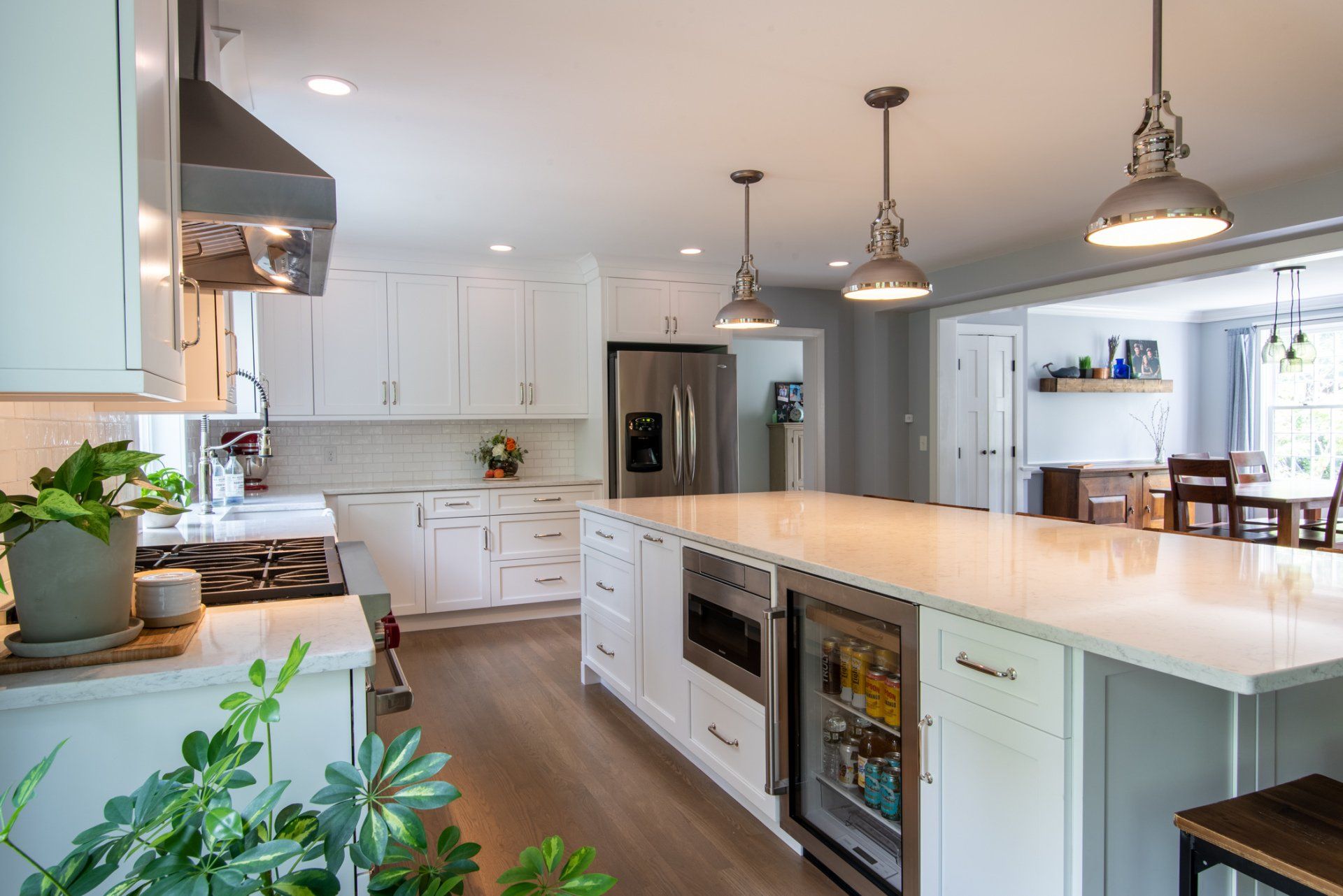Bright modern kitchen with white cabinets, large island, pendant lights, and hardwood floors