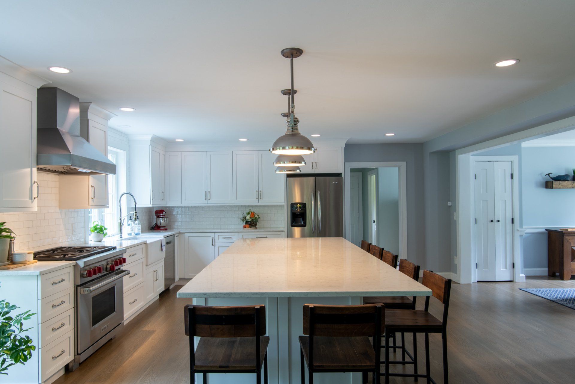 Bright modern kitchen with white cabinets, large island, pendant light, and bar stools