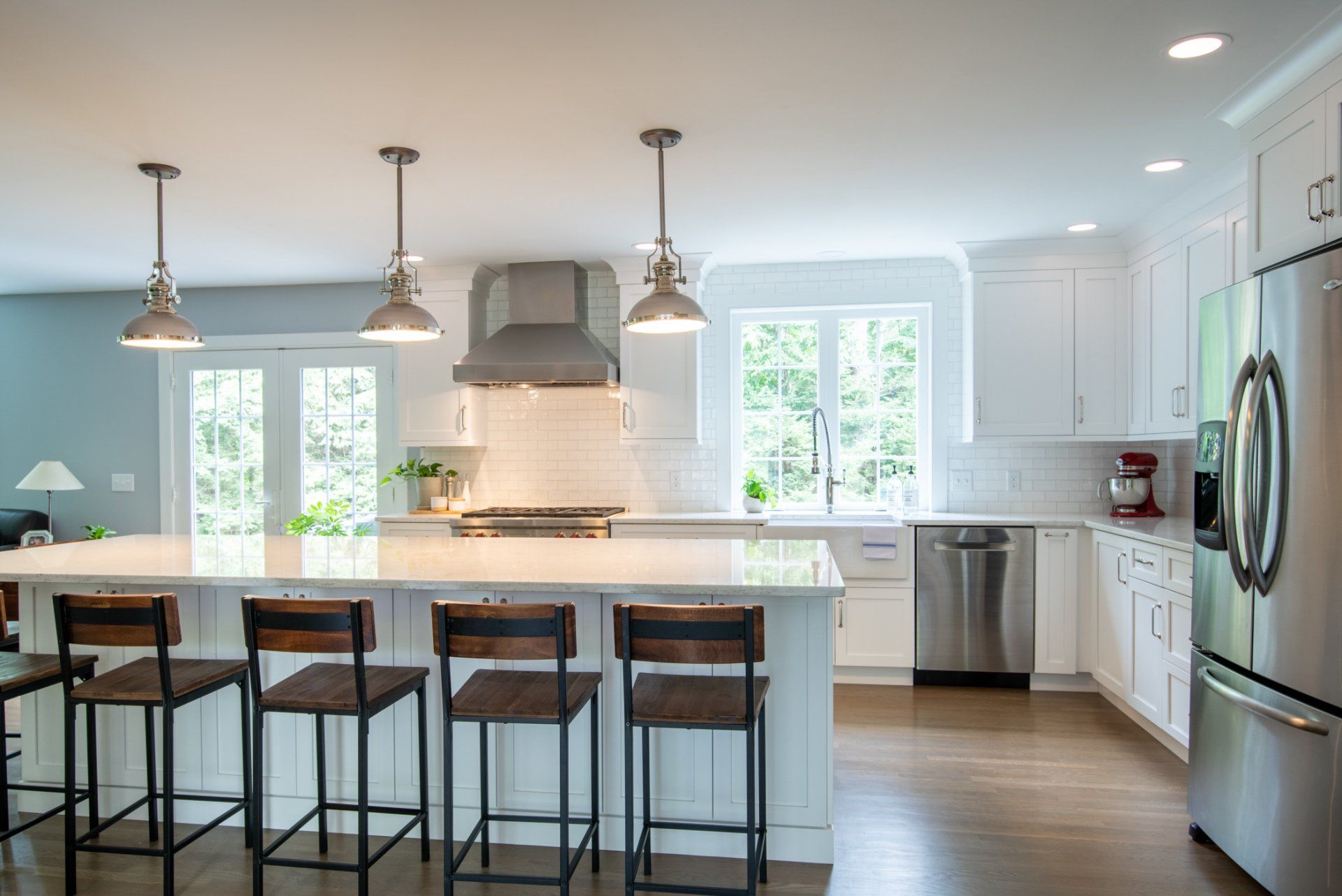 Bright modern kitchen with island, bar stools, white cabinets, and stainless steel appliances