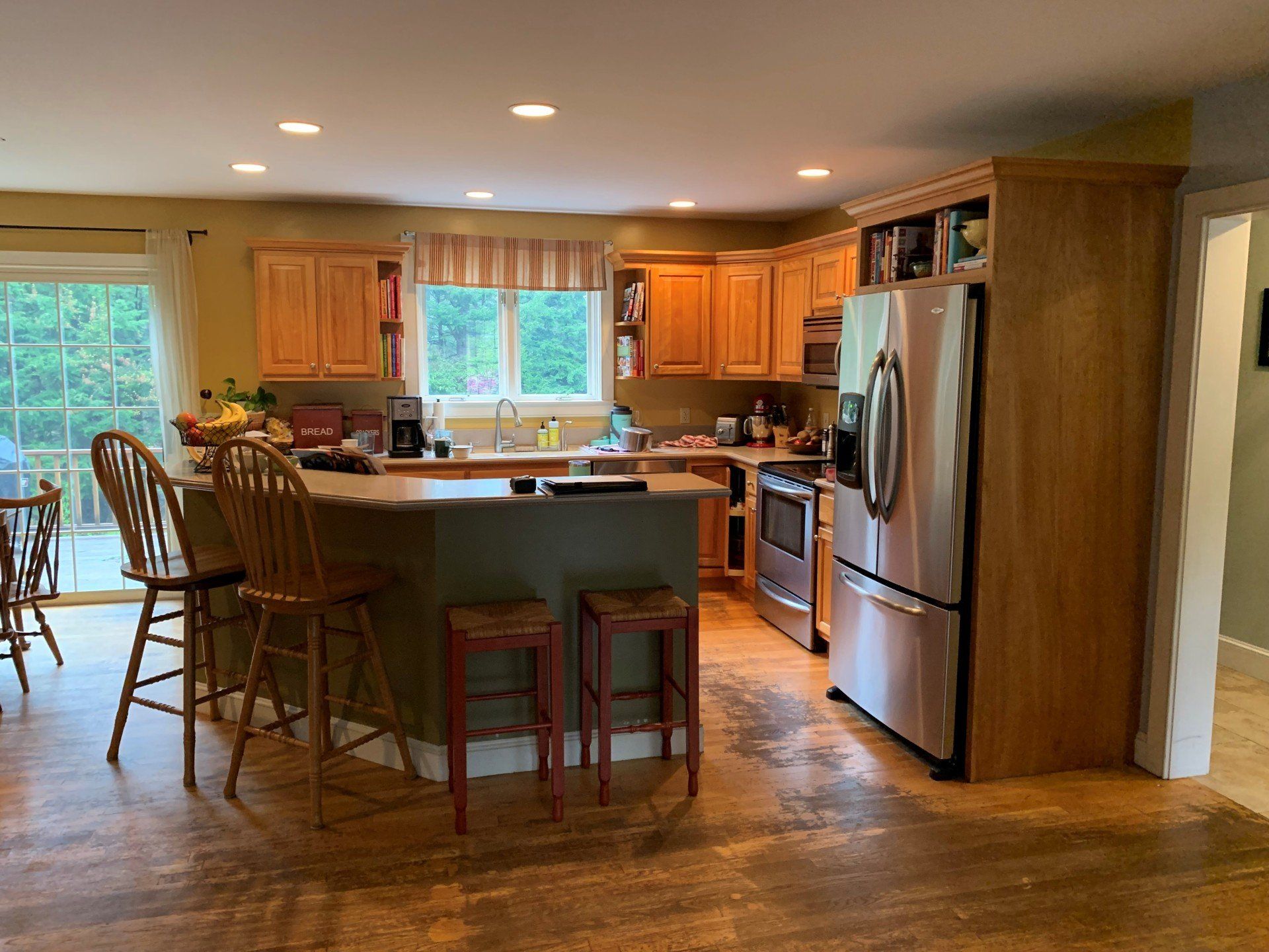 Spacious kitchen with wood cabinets, stainless fridge, center island, and bar stools by a bright window