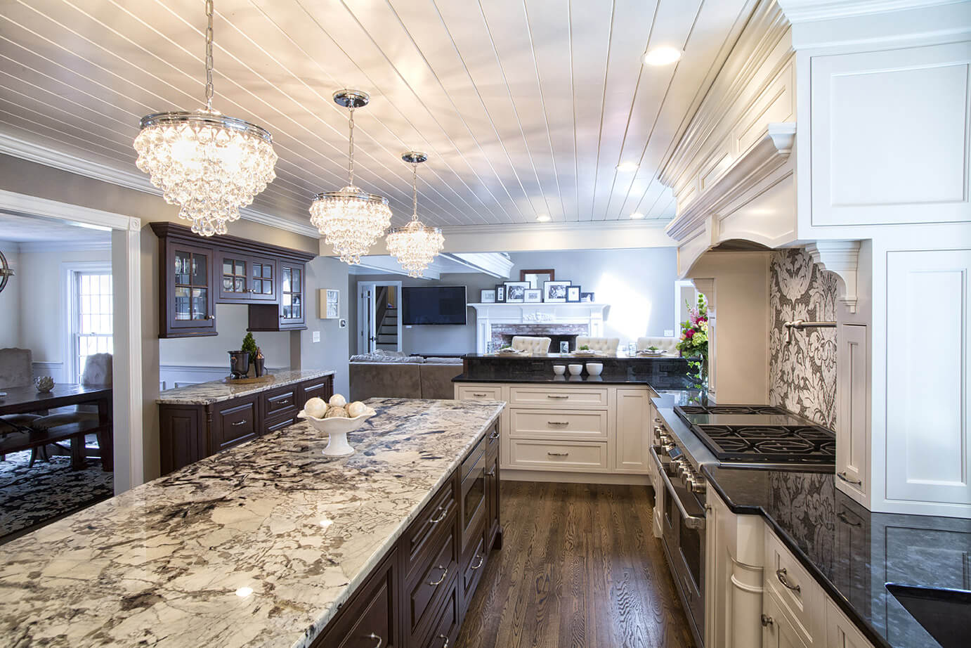 Elegant kitchen with granite island, crystal chandeliers, black countertops, and wood floors