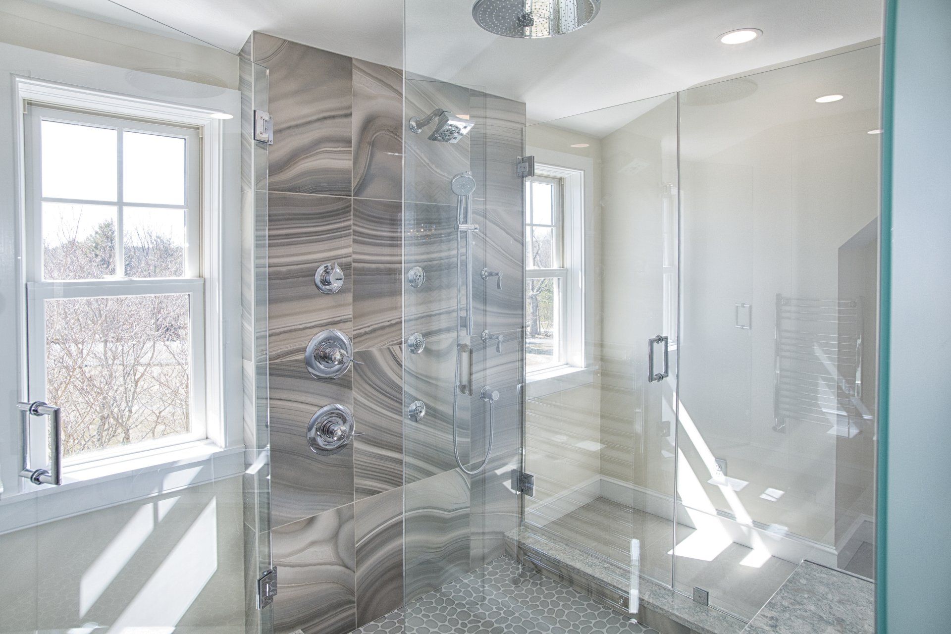 Modern bathroom with glass shower enclosure, marble tile, and bright windows