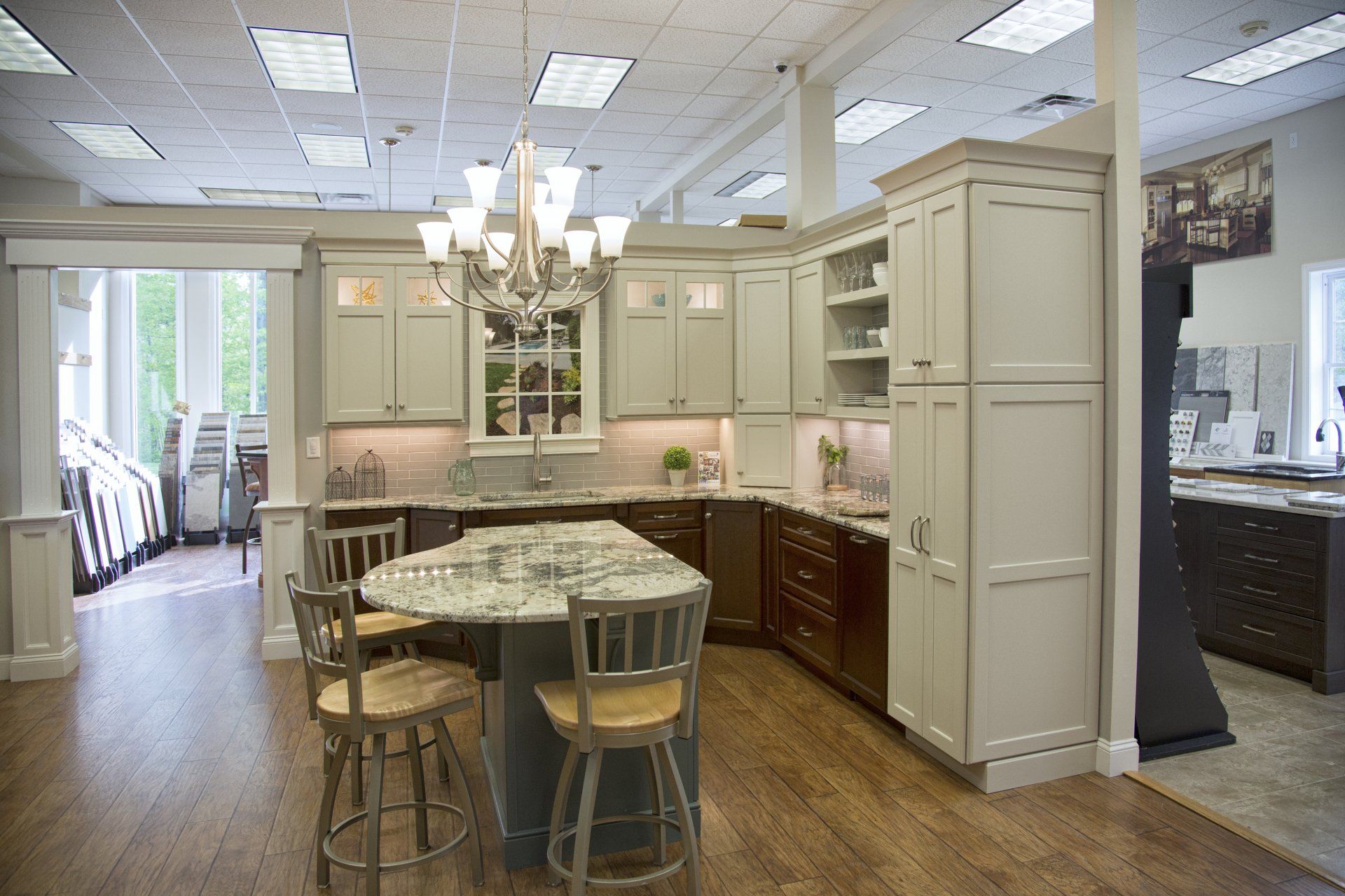 Bright kitchen with white cabinets, island table, wood floors, and chandelier lighting