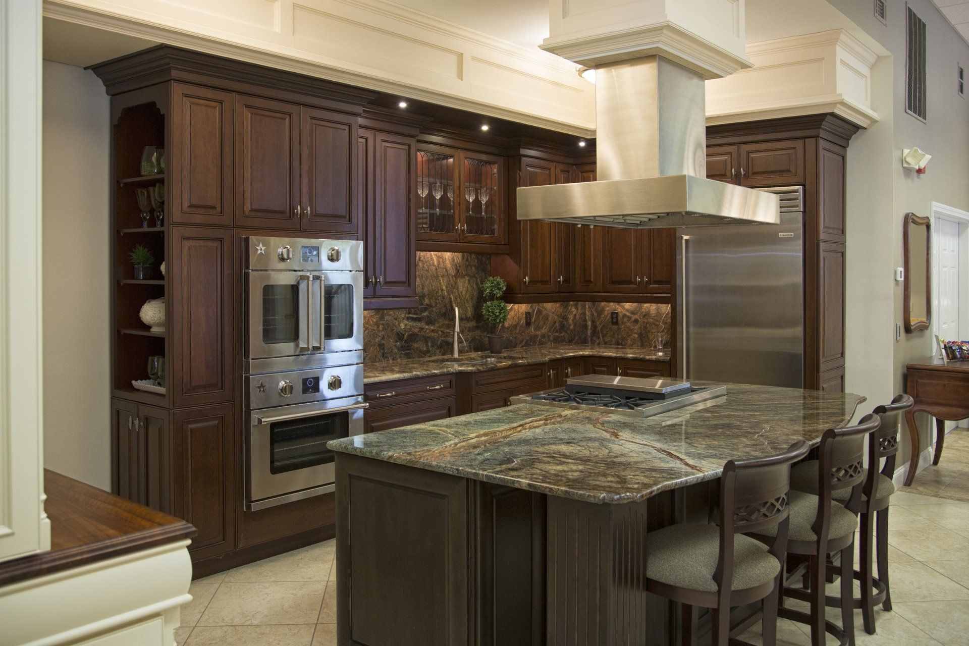 Luxury kitchen with dark wood cabinets, marble island, and stainless-steel appliances