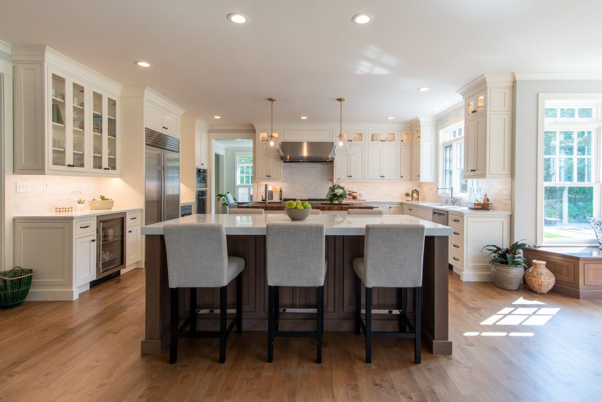 Bright modern kitchen with white cabinets, island seating, and hardwood floors