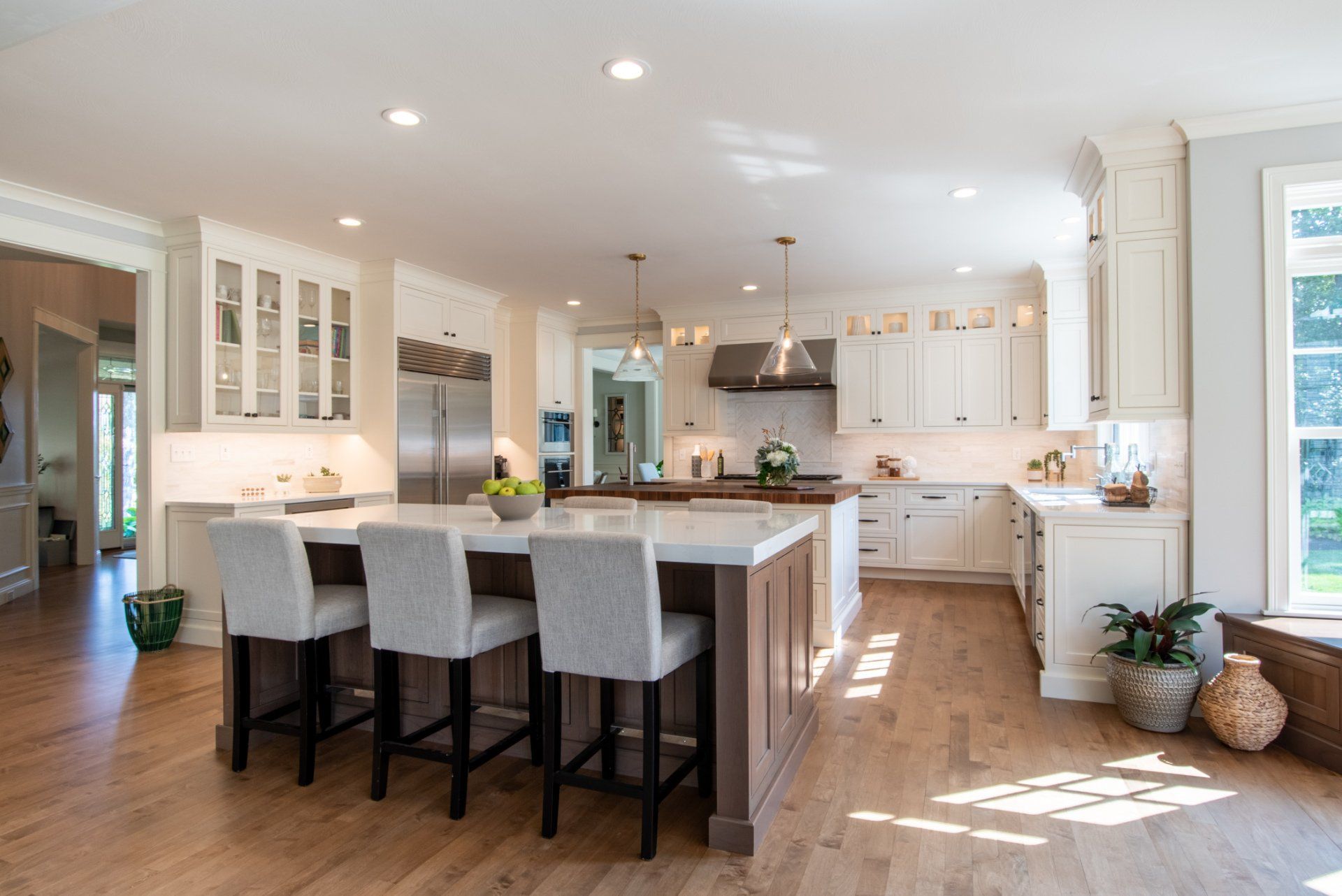 Bright modern kitchen with white cabinets, island seating, and hardwood floors