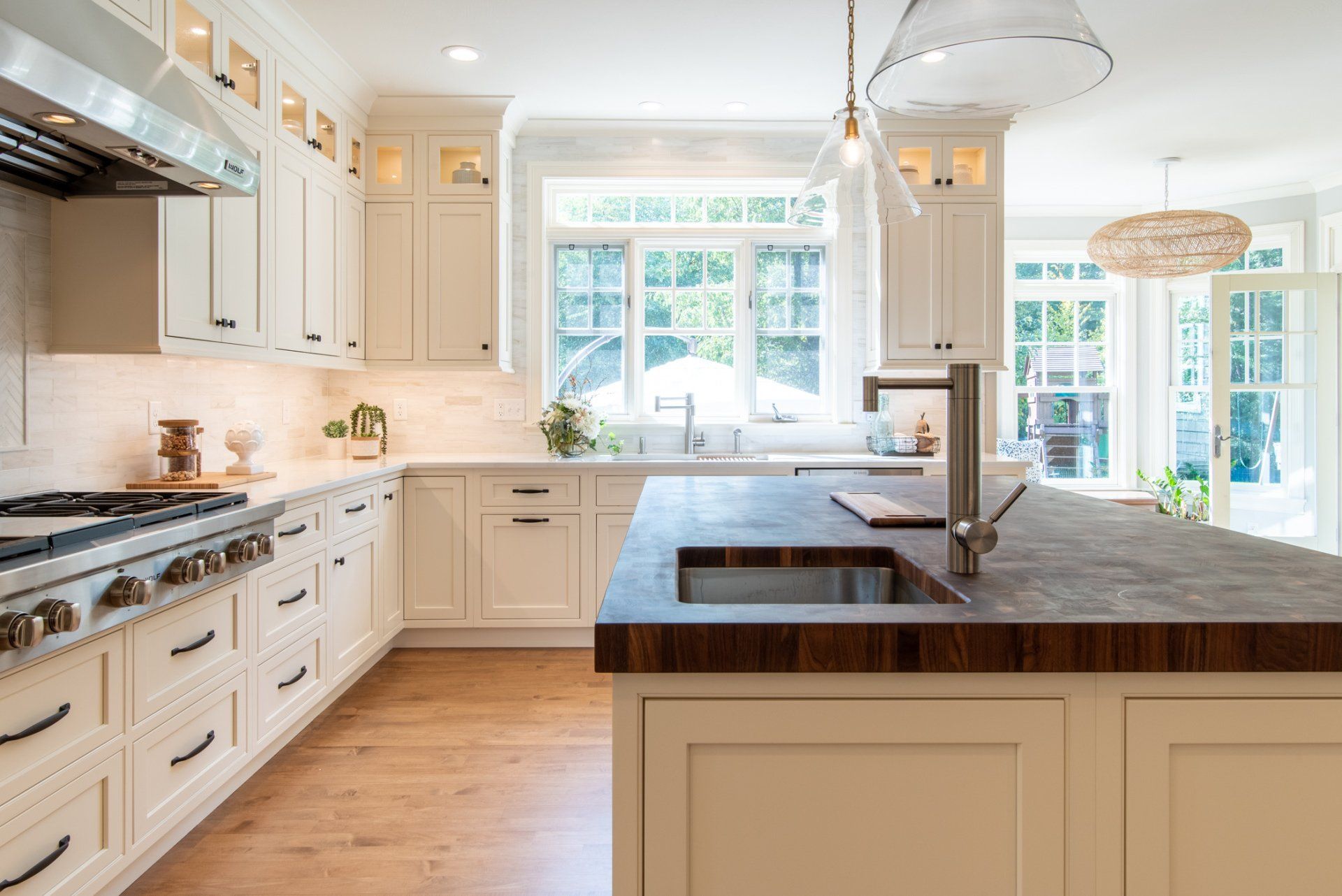 Bright white kitchen with a large island, farmhouse sink, and sunlit windows