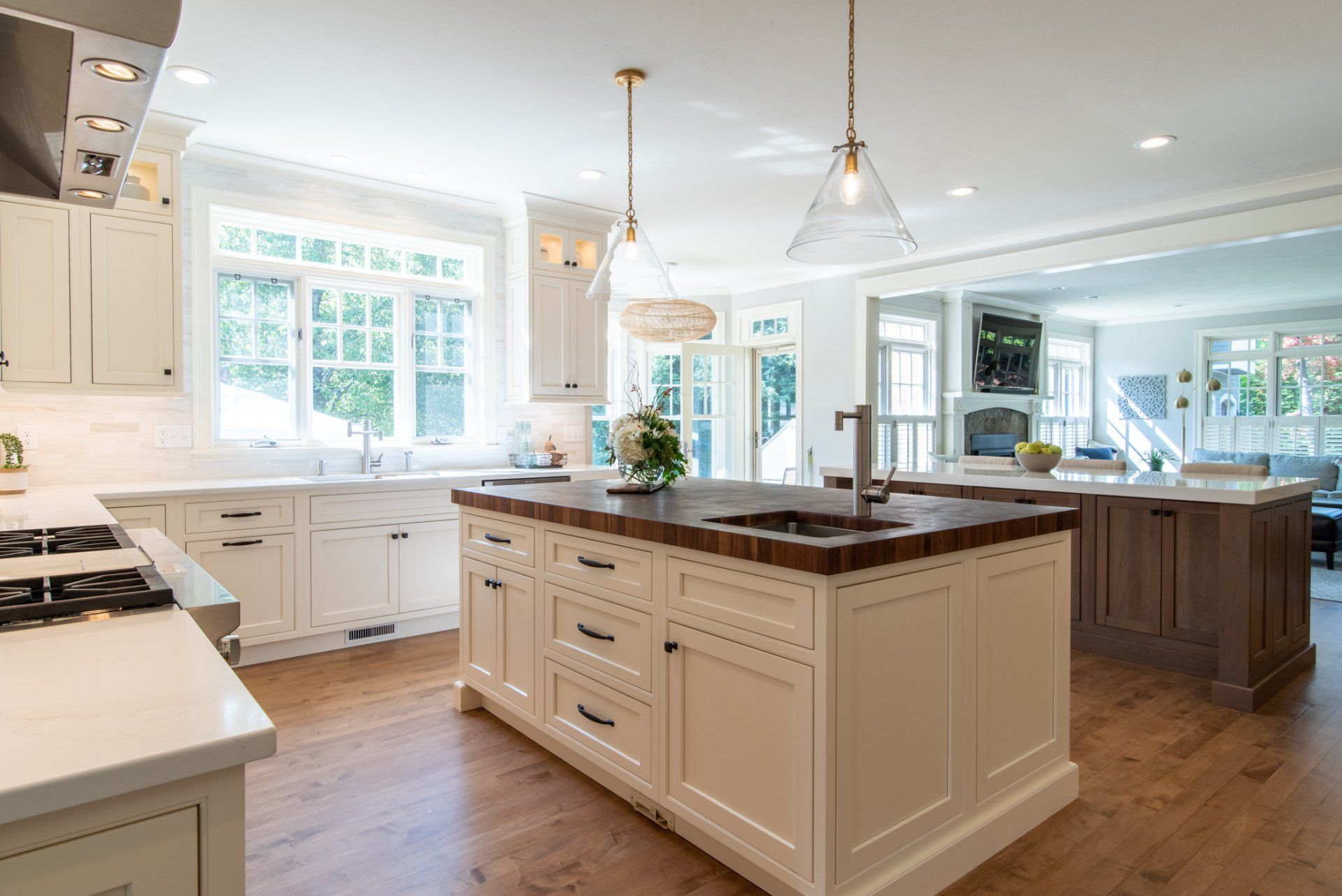 Bright modern kitchen with white cabinets, wood island, and large windows