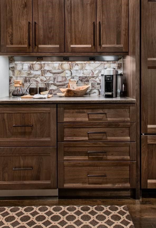 Wooden kitchen cabinets and drawers with a countertop, backsplash, and small coffee maker above a patterned rug