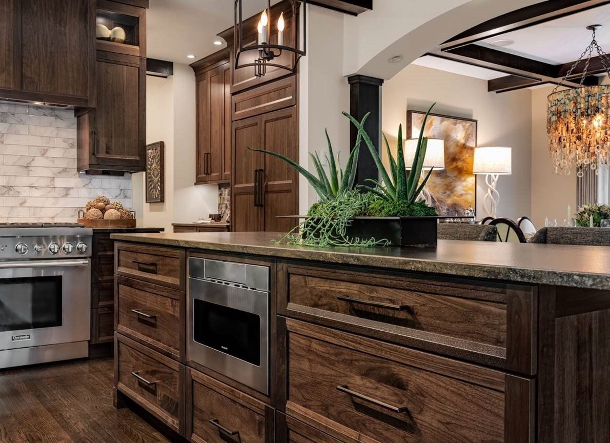 Modern kitchen with dark wood cabinets, granite island, stainless stove, and arched entryway