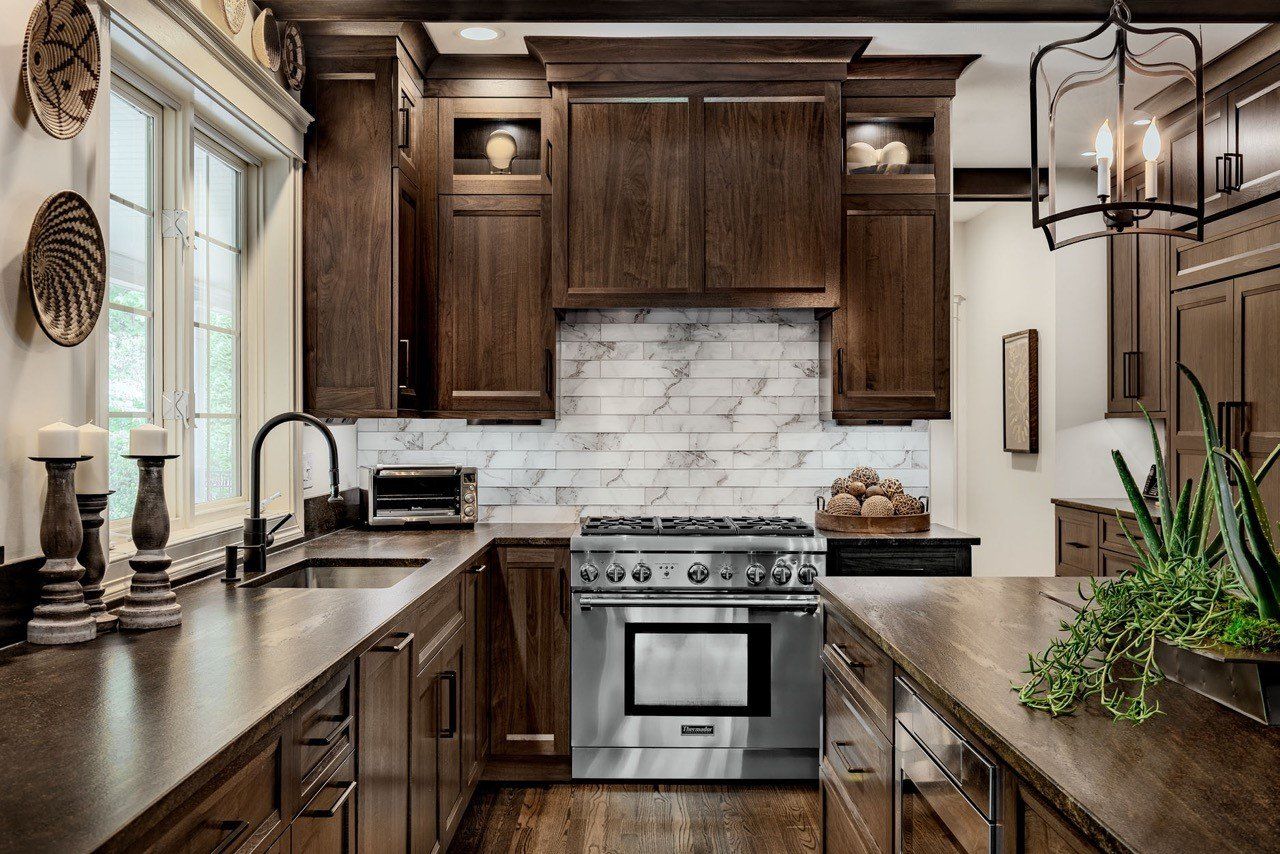 Modern kitchen with dark wood cabinets, marble backsplash, stainless stove, and two countertops