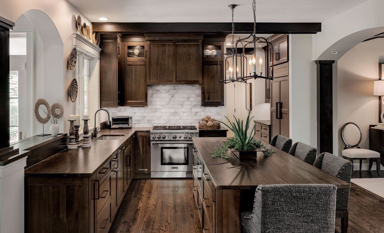 Modern kitchen with dark wood cabinets, marble island, stainless stove, and pendant lights