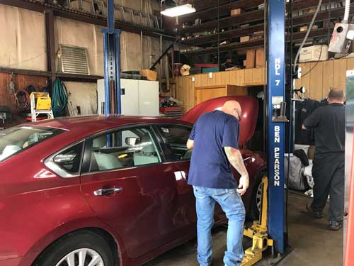 A man is working on a red car in a garage.