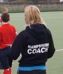 A woman wearing a black hoodie that says hampshire coach
