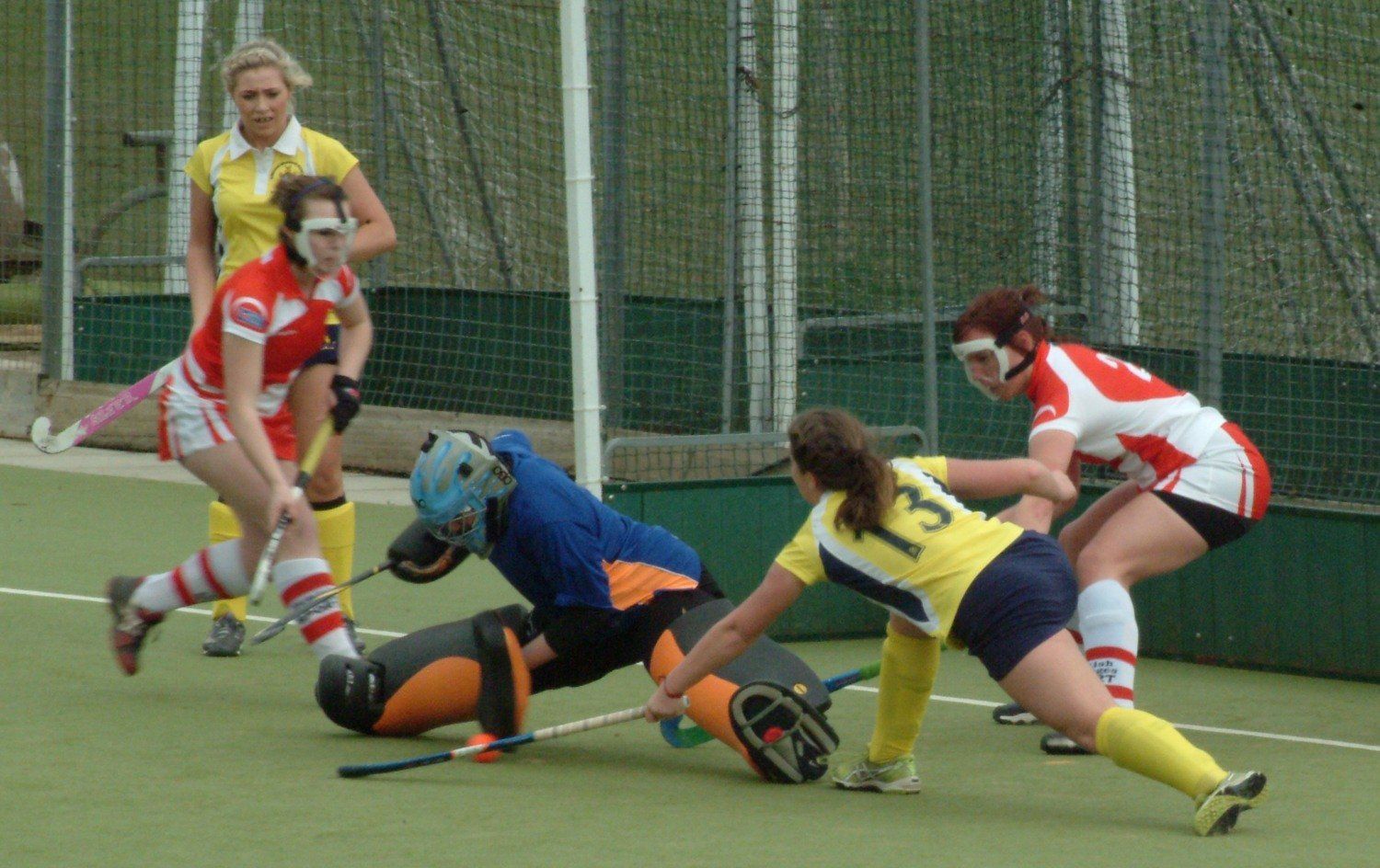 A group of female field hockey players are playing a game