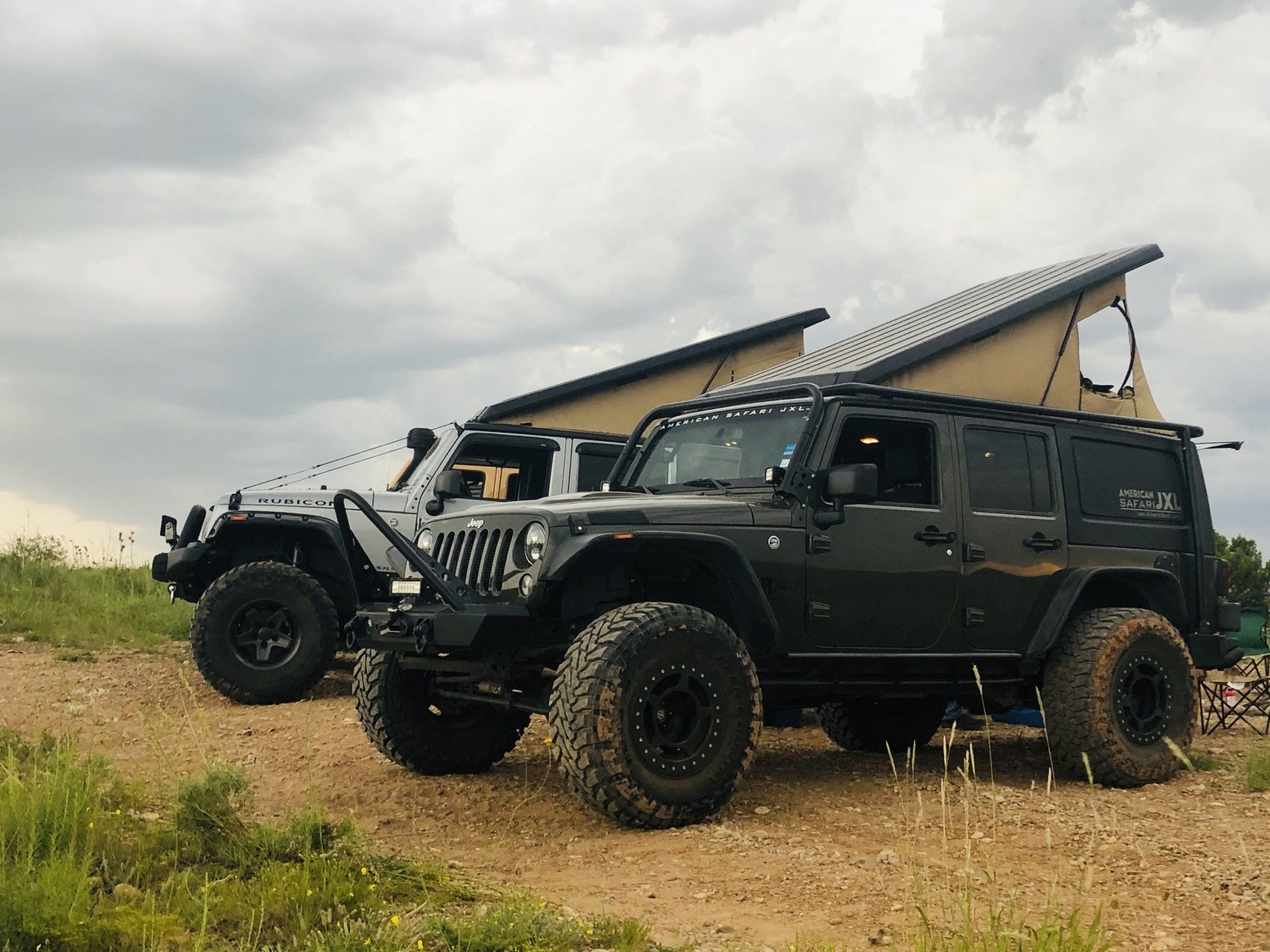 Two American Safari JXLs are parked next to each other in a dirt field.