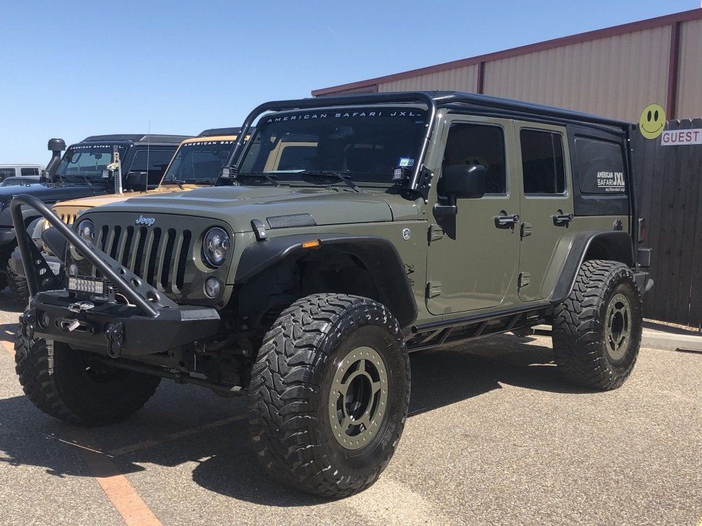 A green jeep JXL is parked in a parking lot in front of a building.