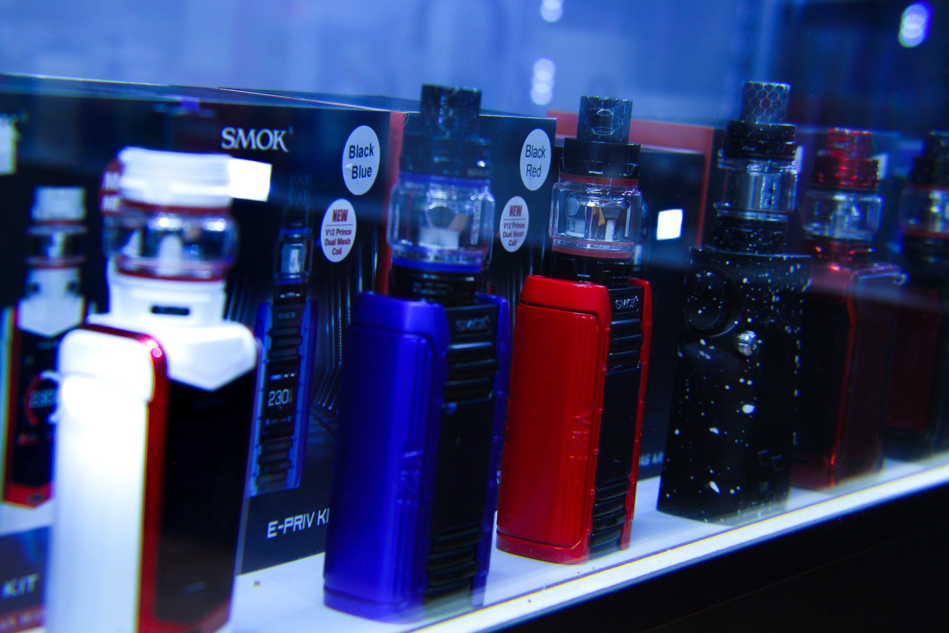 A variety of electronic cigarettes are displayed on a shelf.