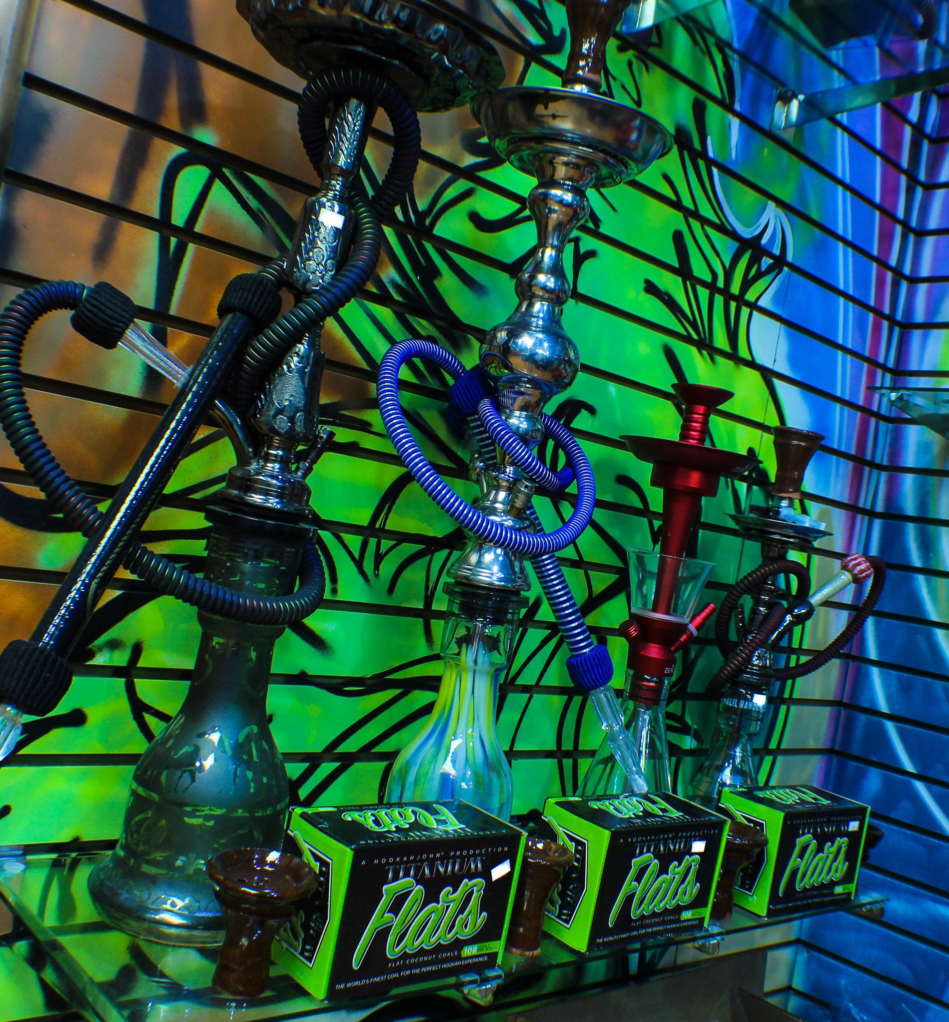 Hookahs are lined up in front of a wall that has graffiti on it