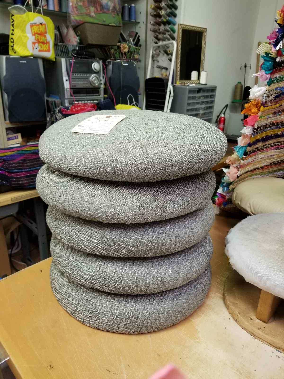 Stack of four gray round cushions on a wooden table in a shop