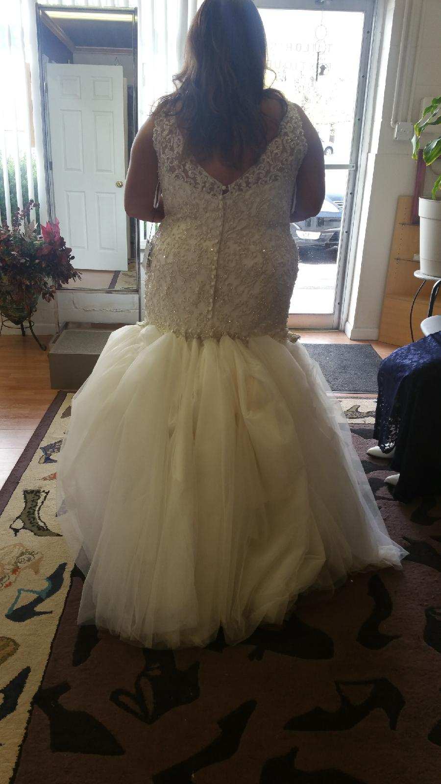 Person in a white formal gown seen from behind in a doorway, with a tulle skirt and beaded bodice.