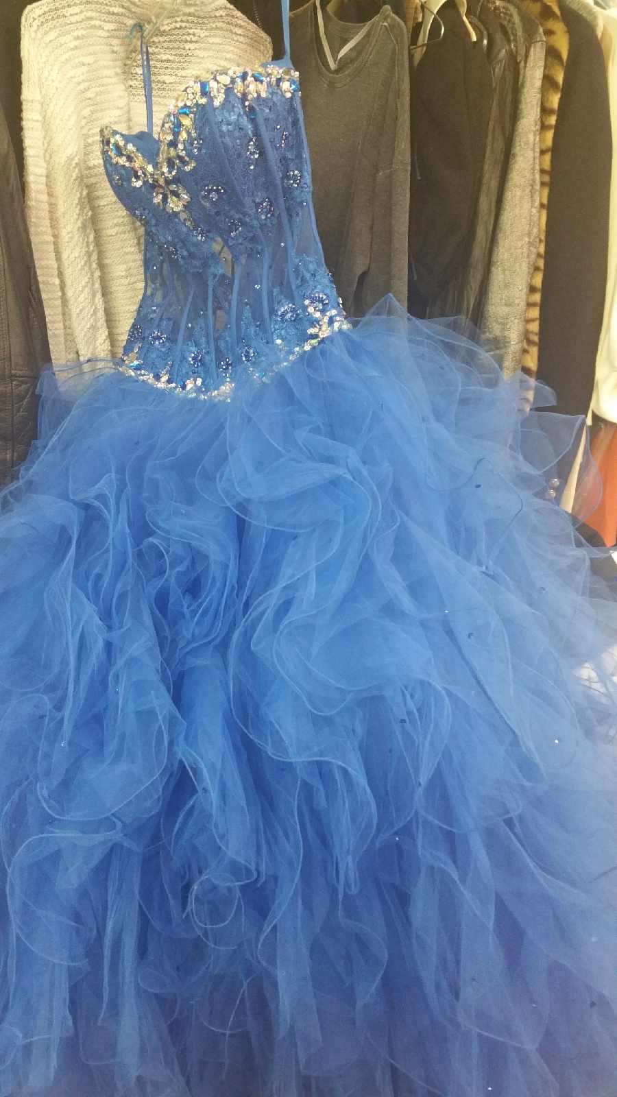 Blue strapless sequined ball gown with a full tulle skirt hanging on a clothing rack