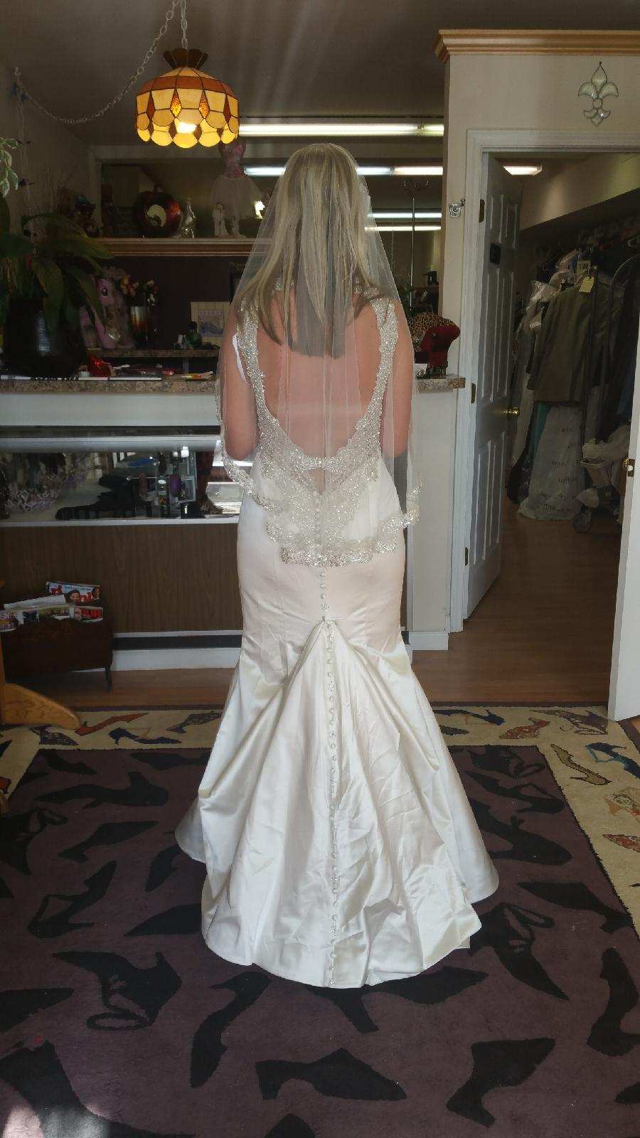Woman in a white wedding dress viewed from behind in a bridal shop