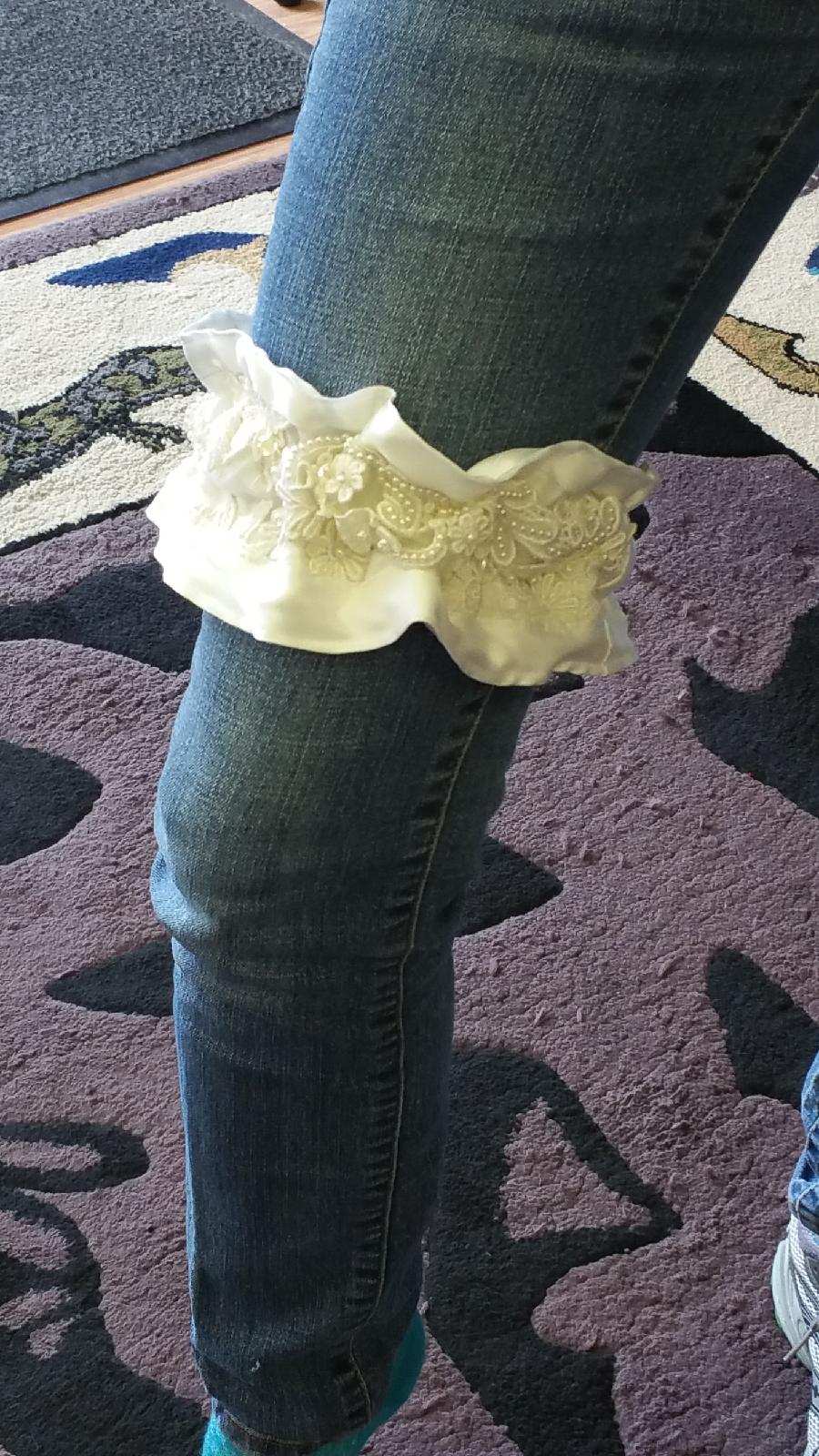 Person in jeans wearing a large white bone-shaped object around one leg.
