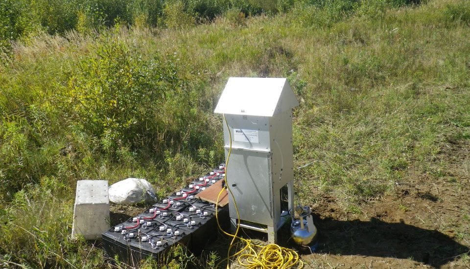 Une petite boîte blanche se trouve au milieu d’un champ herbeux.
