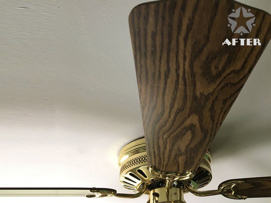 Close-up of a ceiling fan with a wood-grain blade and brass motor on a white ceiling