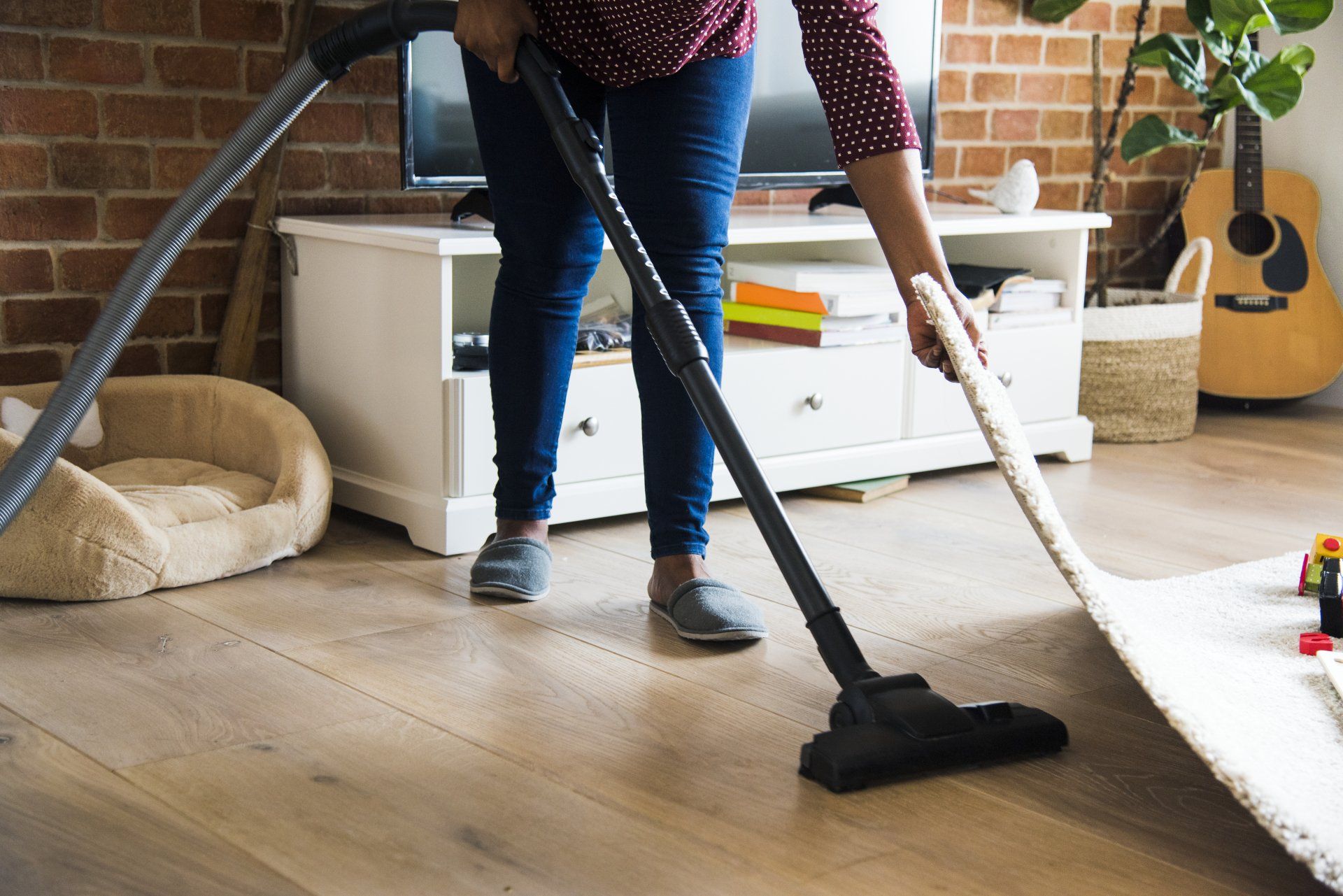 Cleaning Carpet - Olney, Maryland - Star Maids Cleaning Solutions LLC Person vacuuming a wooden floor in a bright living room