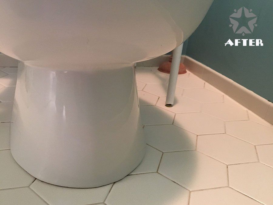 White toilet on white hex tile floor with a small metal support leg nearby