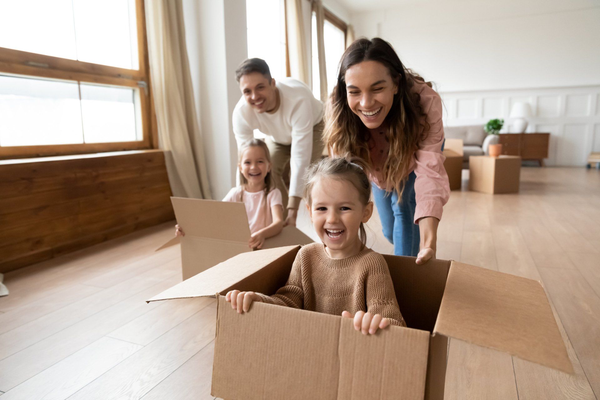 Happy Family - Olney, Maryland - Star Maids Cleaning Solutions LLC Family smiling while unpacking a cardboard box in a bright living room