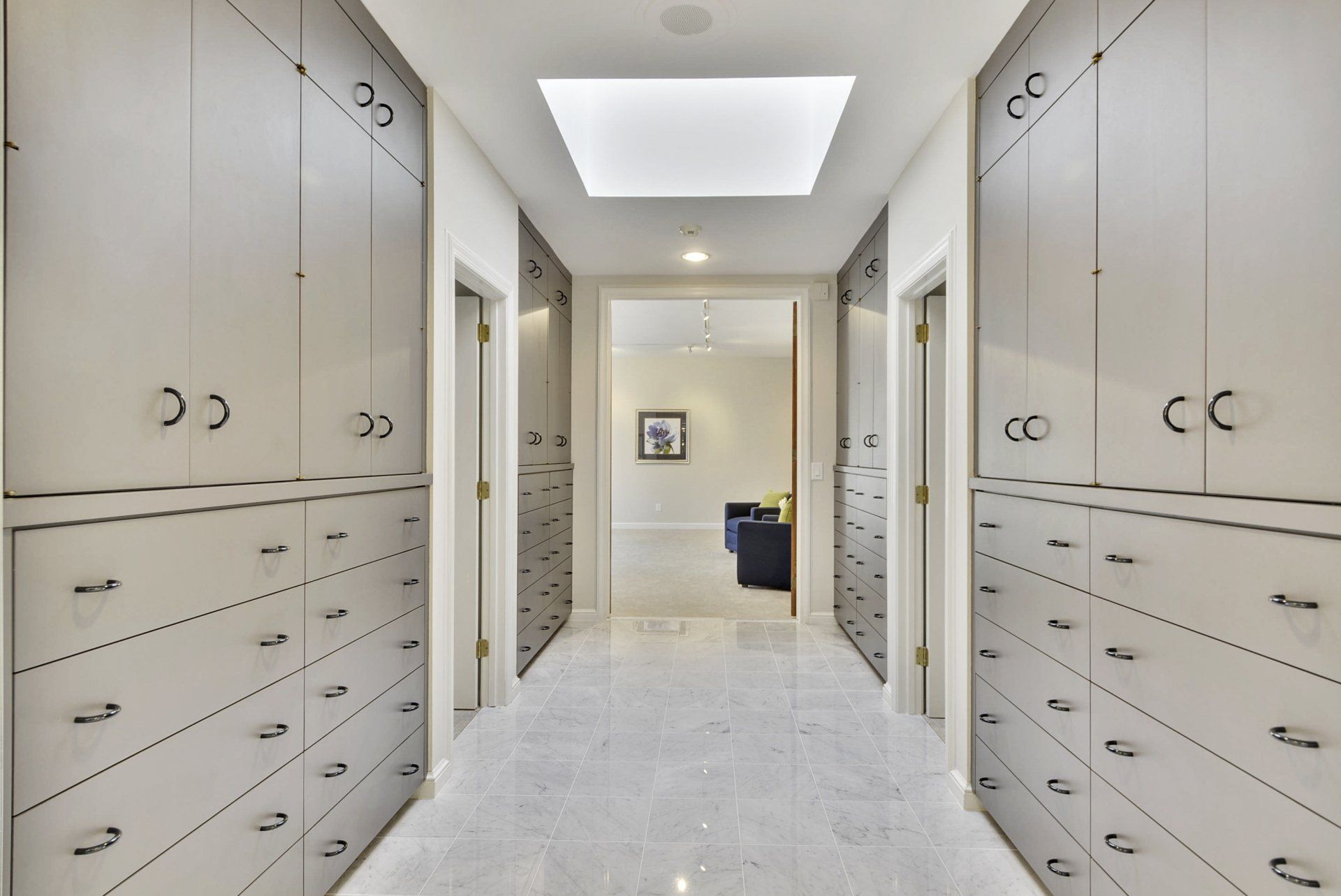 Bright hallway with built-in cabinets and drawers on both sides, leading to a doorway and seating area.