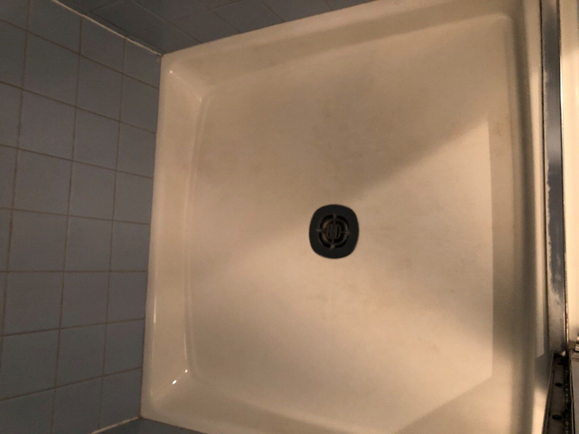 Empty white shower stall with a central drain and tiled bathroom wall