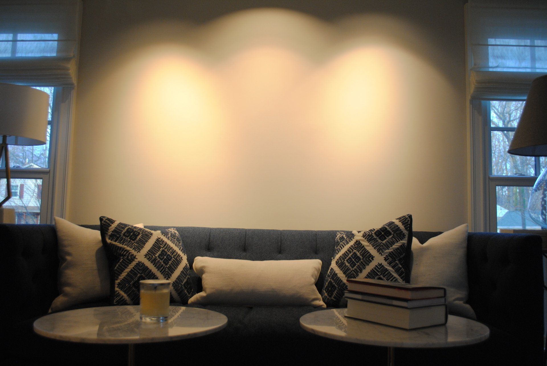 Cozy living room sofa with patterned pillows, two side tables, and warm wall lighting