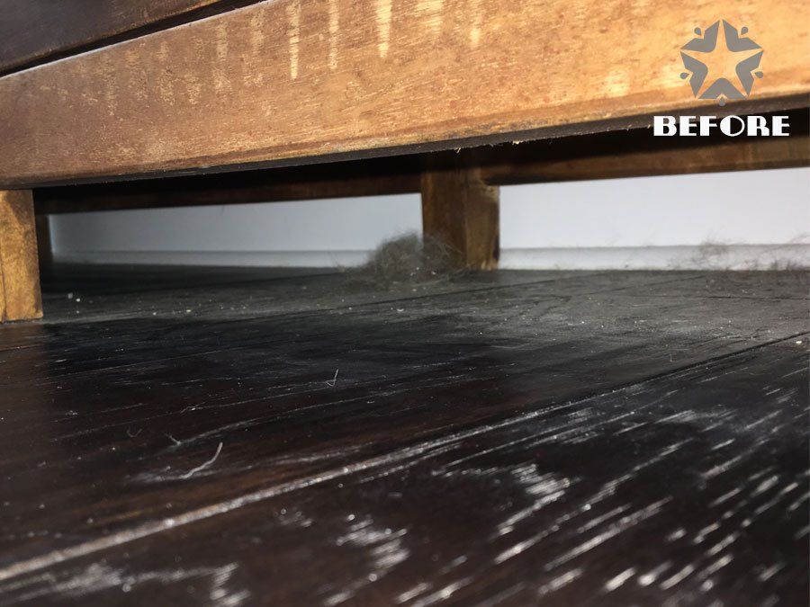 Close-up of scratched dark wood floor beneath a wooden surface, with a “BEFORE” label in the corner