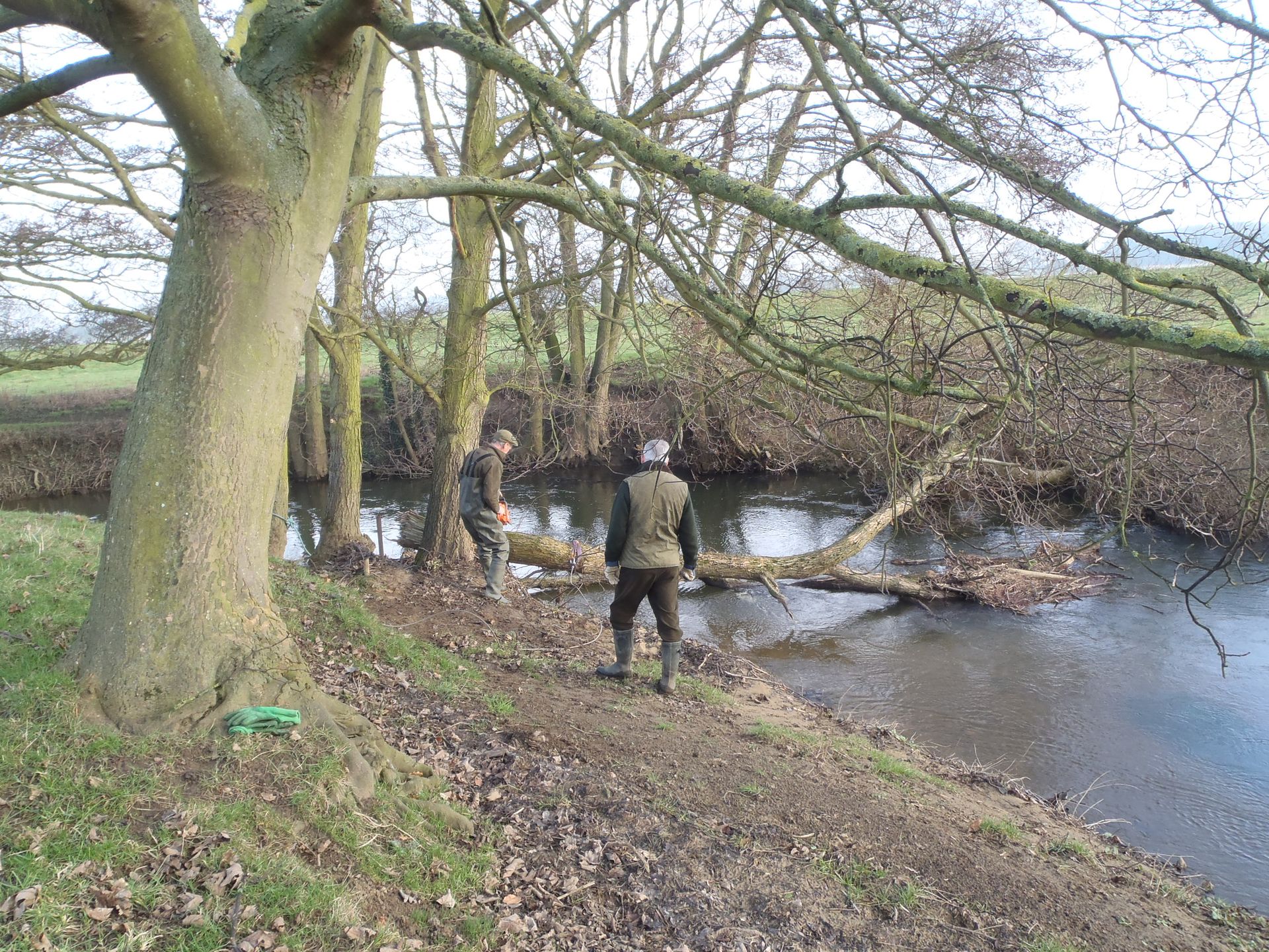 A man is standing on a path next to a river.
