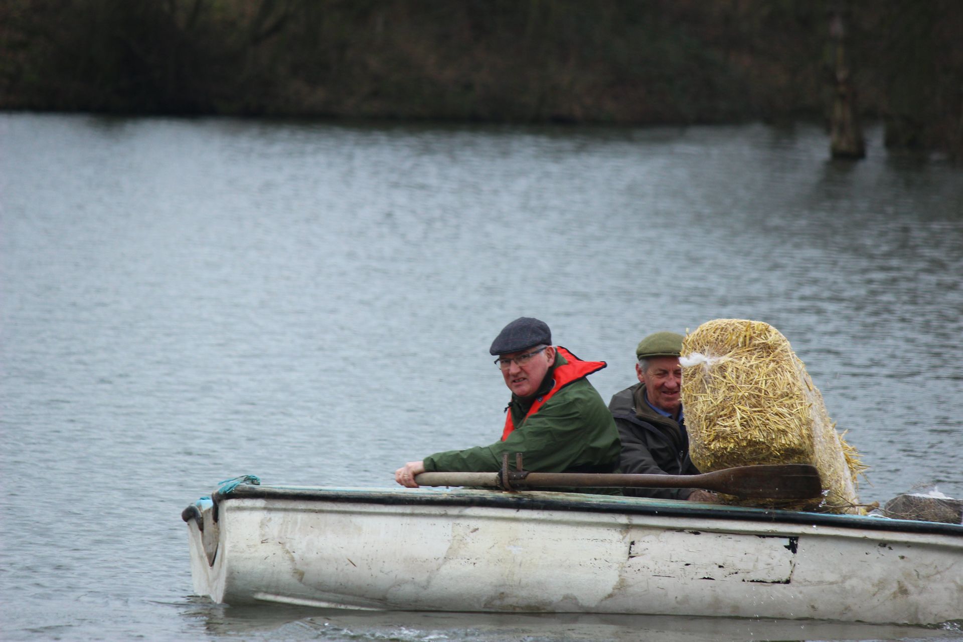 Two men are rowing a boat on a lake.