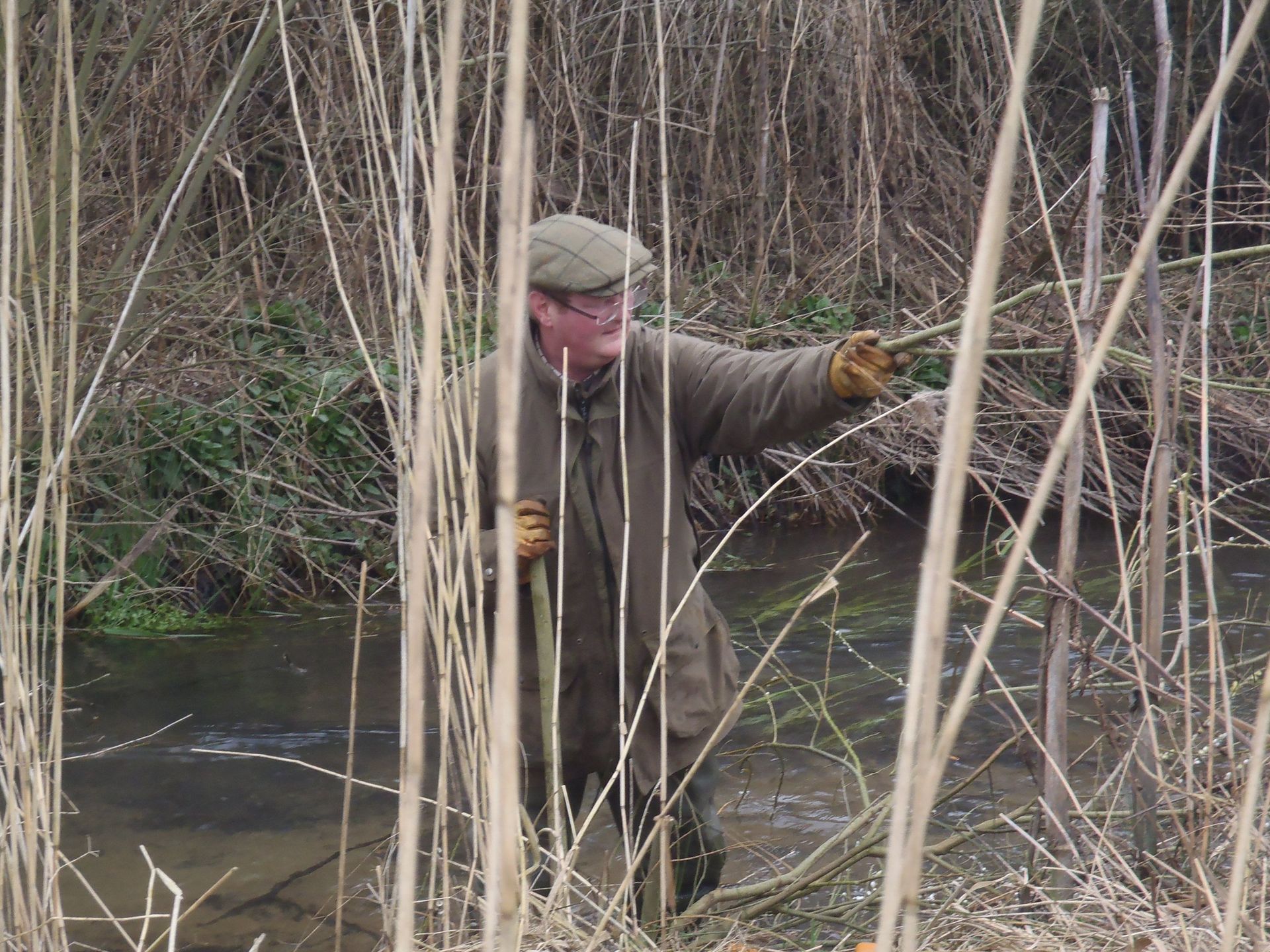 A man is standing in the tall grass near a river
