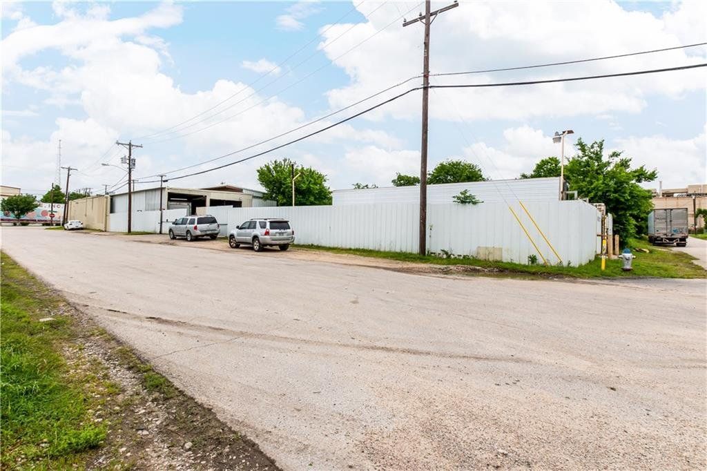 A gravel road with cars parked on the side of it.