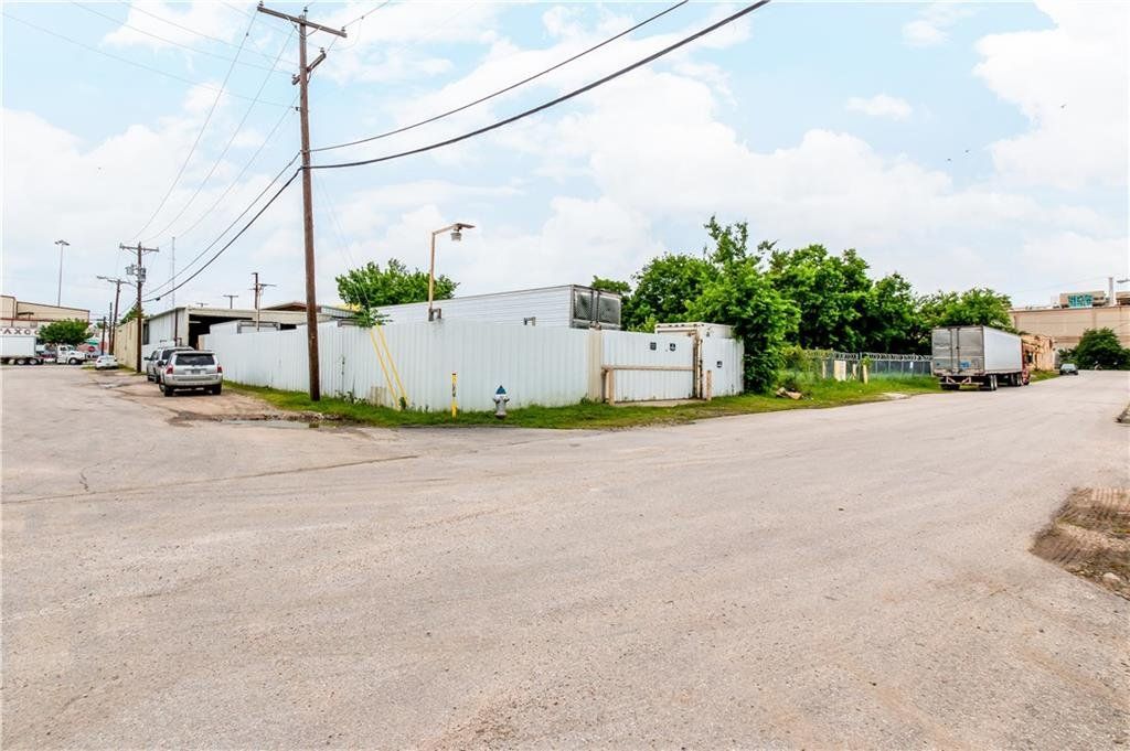 A gravel road with a white building in the background