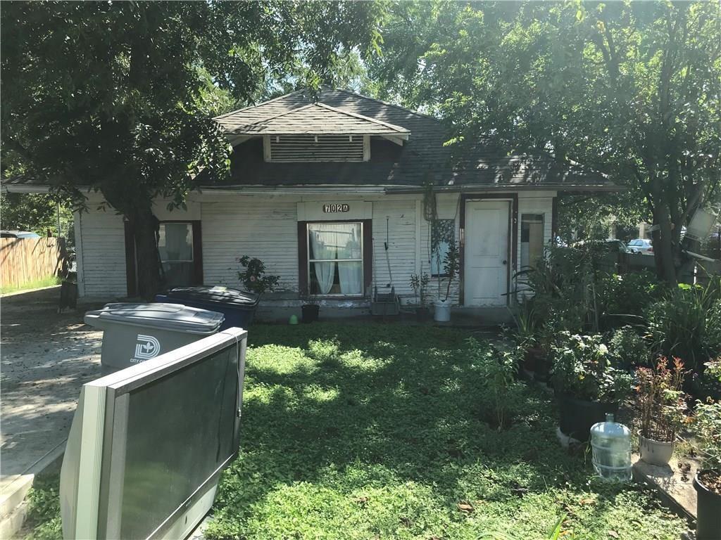 A tv is sitting in the grass in front of a house.