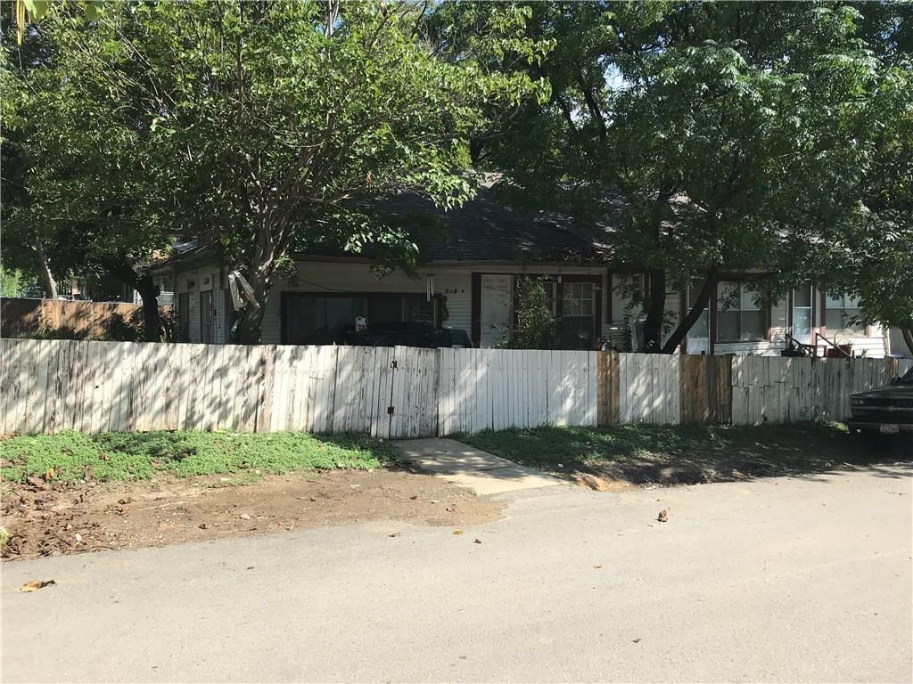 A white pick up truck is parked in front of a house with a white fence.