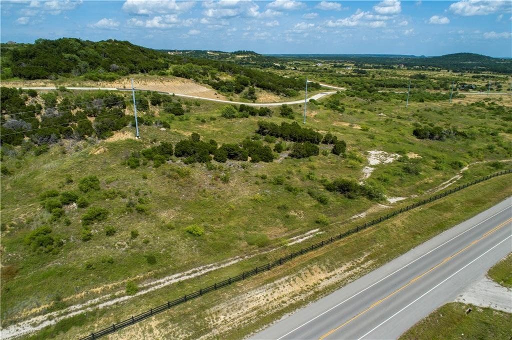 An aerial view of a road going through a grassy field.