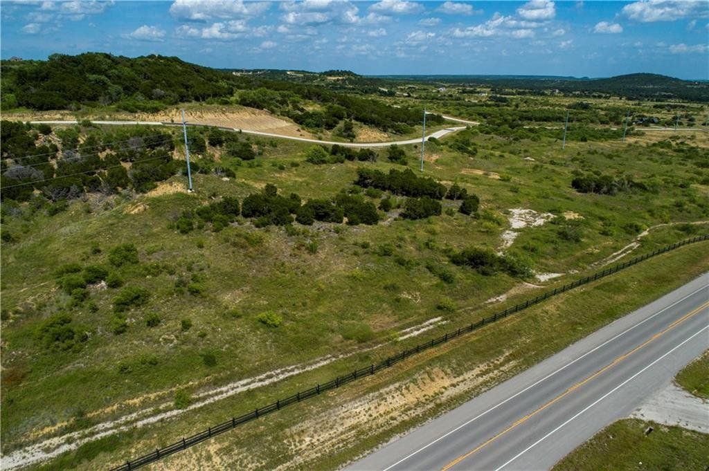 An aerial view of a road going through a grassy field.