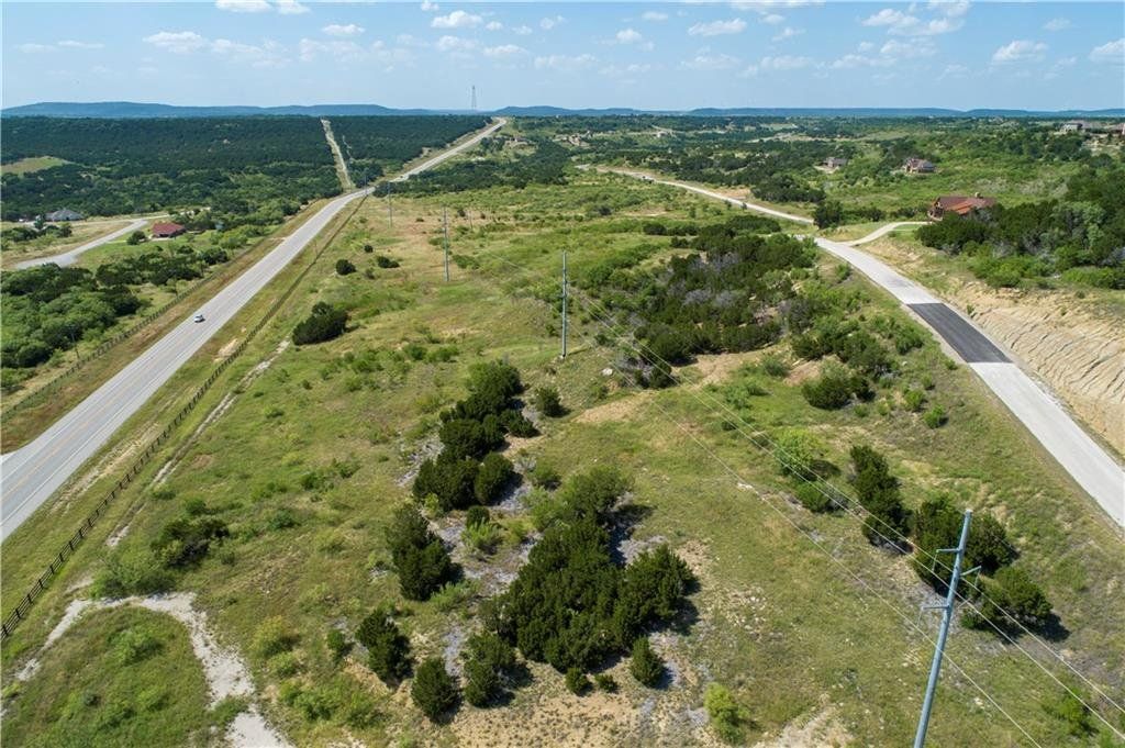 An aerial view of a road going through a grassy field.